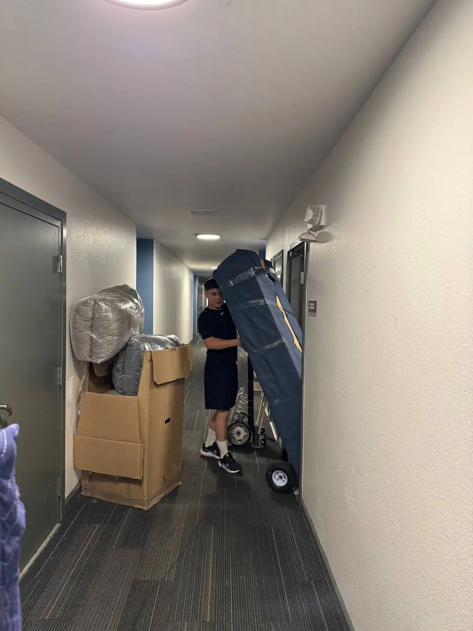 Mover rolling a wrapped item down an apartment hallway
