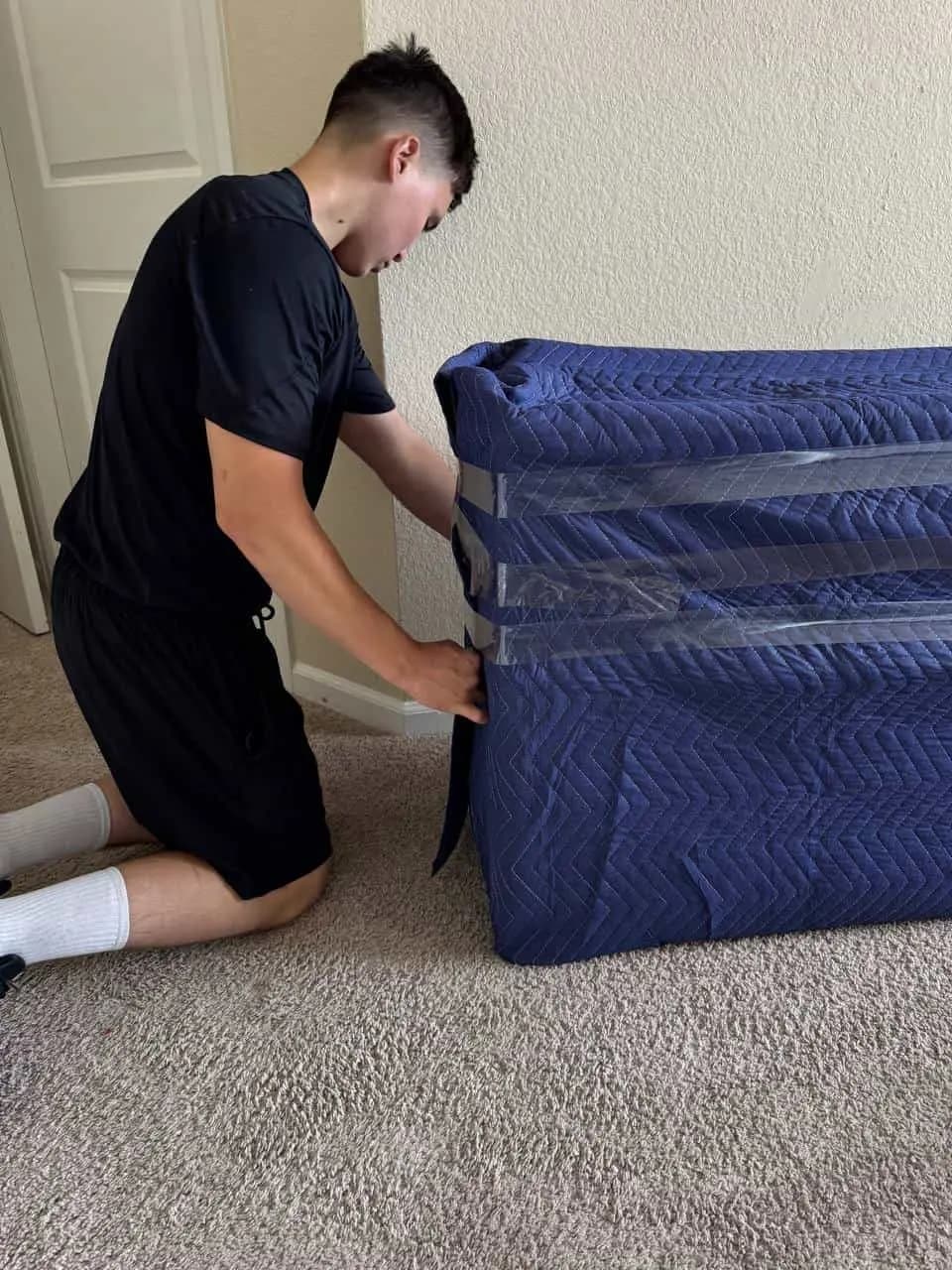 Mover strapping blue moving blankets around furniture