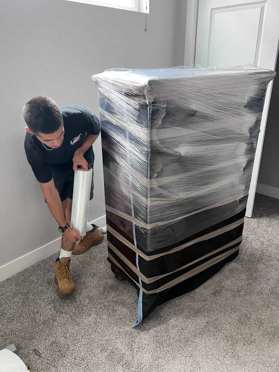 Mover shrink-wrapping a dresser